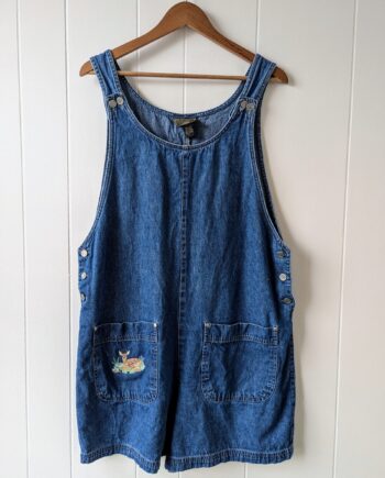 Vintage denim coveralls with three buttons on each side and two front pockets. the front right pocket features custom embroidery of a fawn laying peacefully amongst flowers.