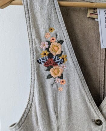 Right panel embroidery detail with gold tiger moth and a bouquet of flowers