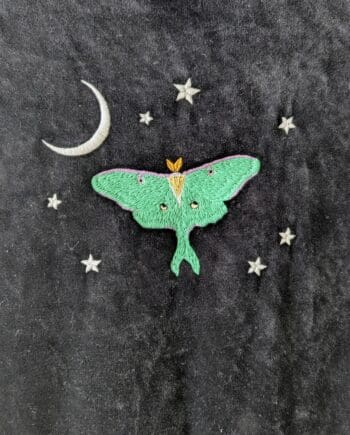 Detail of the embroidery on back of dress. Mint green luna moth with a white crescent moon in the top left of the design, surrounded by seven tiny white stars.